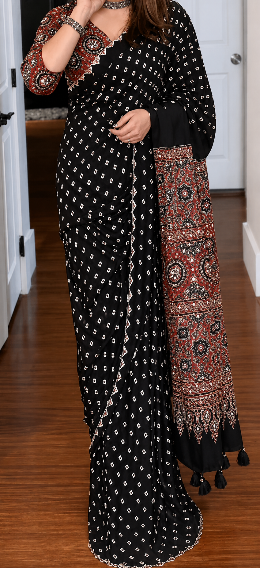 Woman posing in a black Ajrakh printed Modal Silk saree with real mirror work and contrast pallu